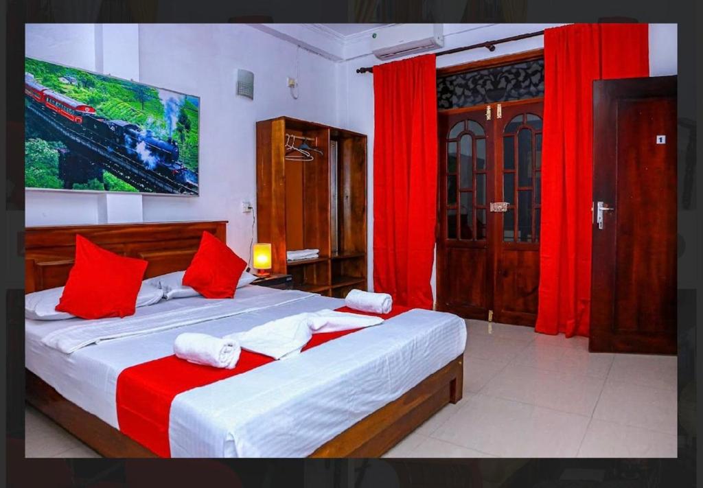 a bedroom with a large bed with red curtains at Elsy Villa Negombo in Negombo
