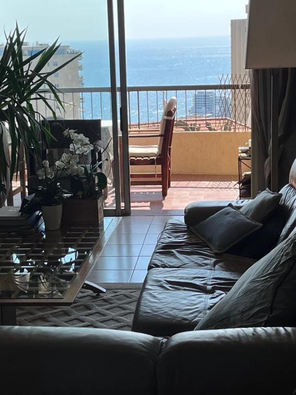 a living room with a couch and a glass table at Une terrasse sur Monaco logement 2 chambre in Beausoleil