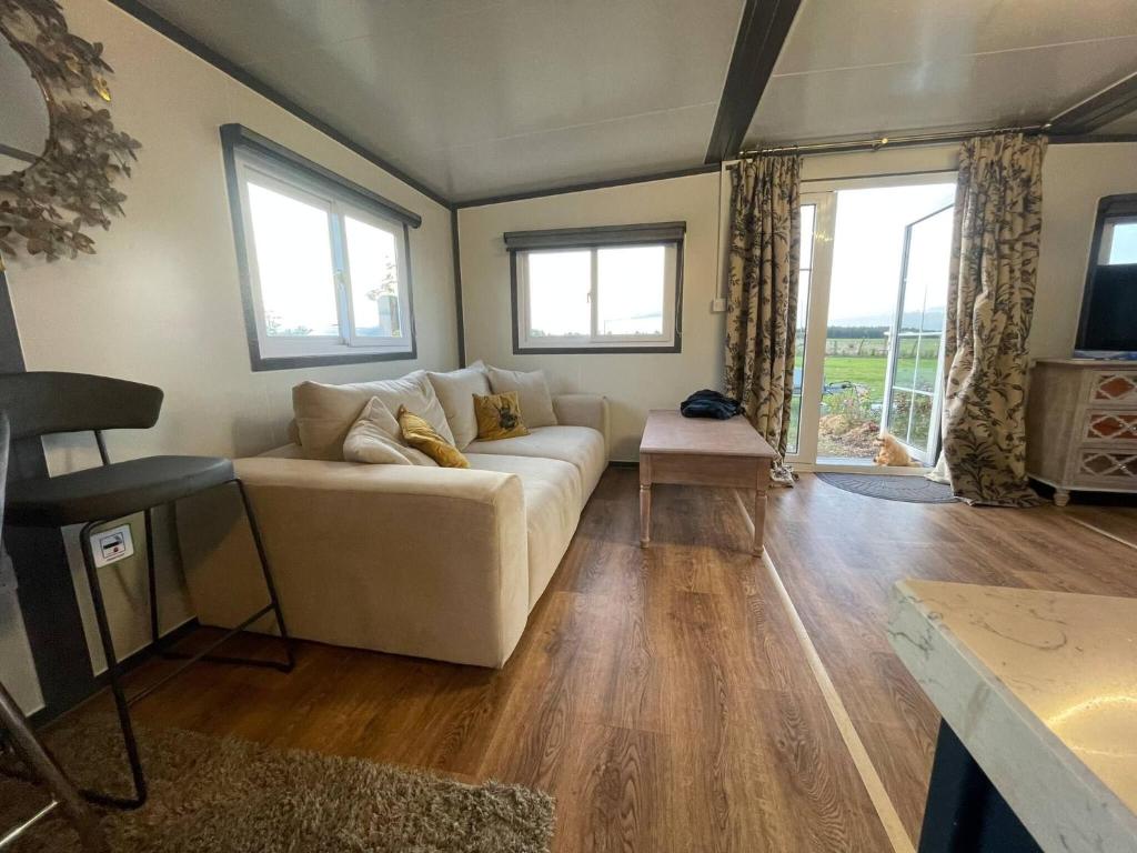 a living room with a couch and some windows at Stunning birch tree Lodge in Otley
