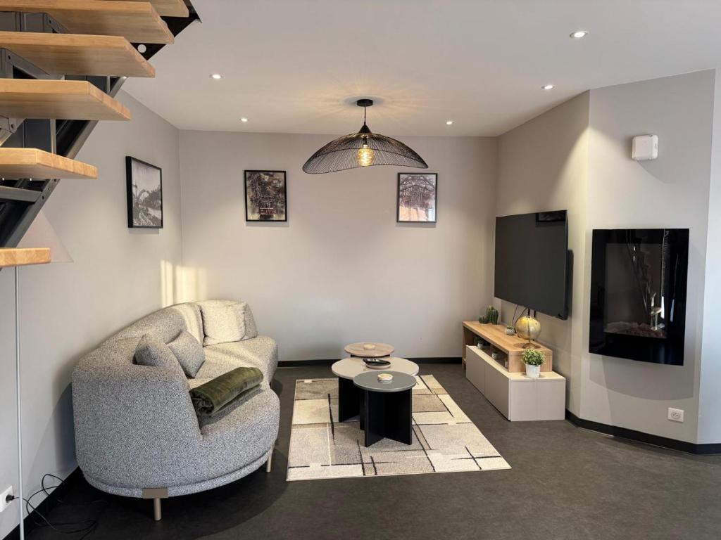 a living room with a chair and a flat screen tv at Résidence du Champ Lamet in Pont-du-Château