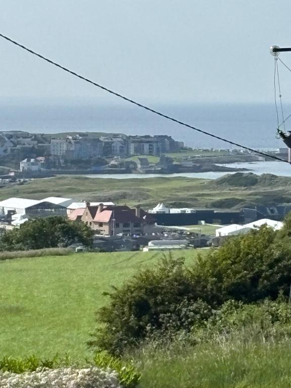 a green field with houses and the ocean in the background at Craigport Cottage in Portrush