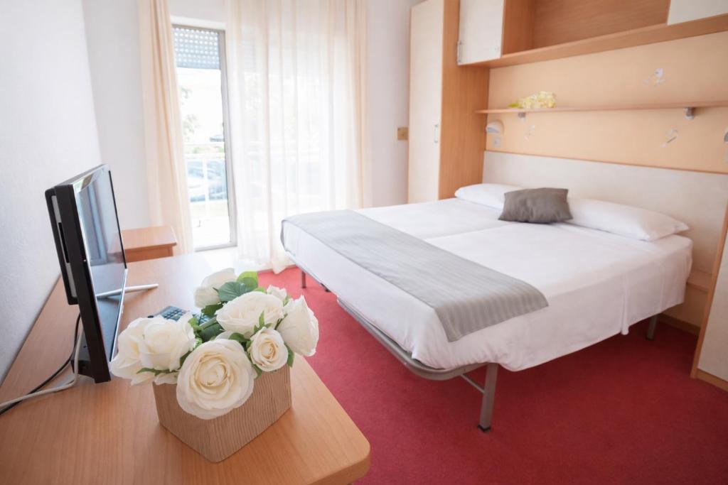 a bedroom with a bed and a tv and flowers at Villa Silvie Rose in Cesenatico