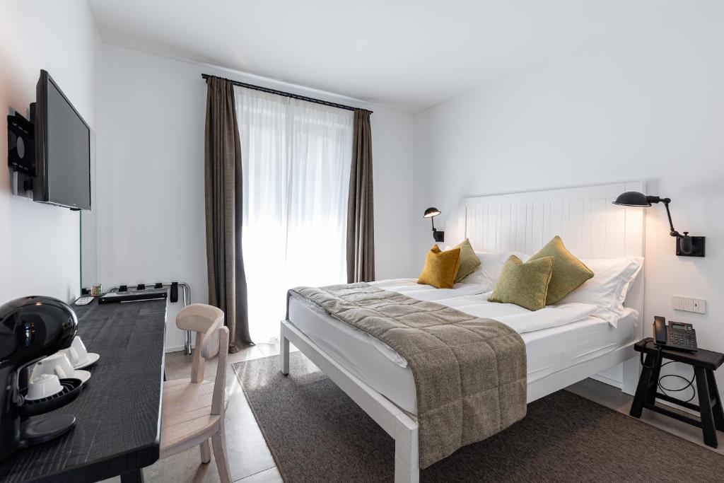 a bedroom with a large white bed with yellow pillows at Seta Hotel in Bellagio