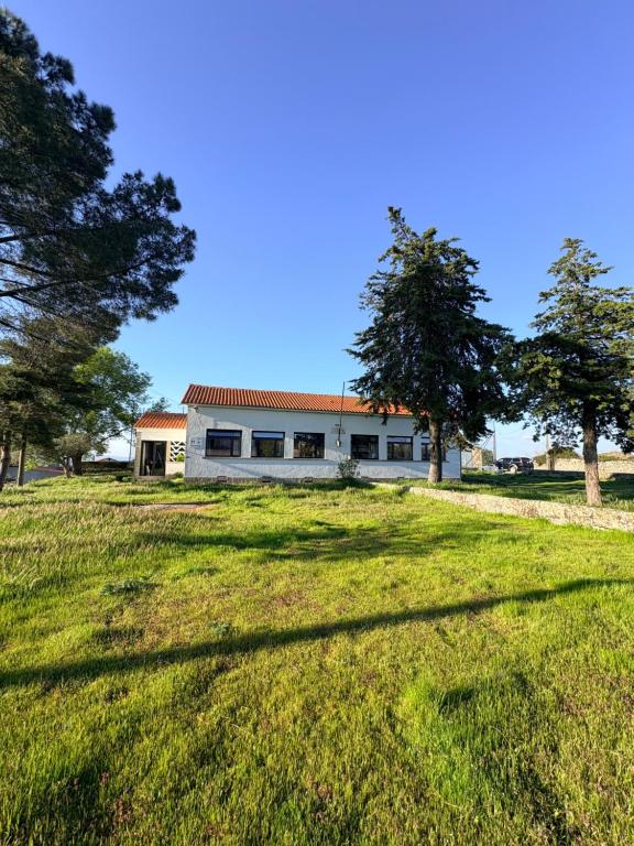 a building with trees in front of a field at Lagartoca in Vilar de Amargo