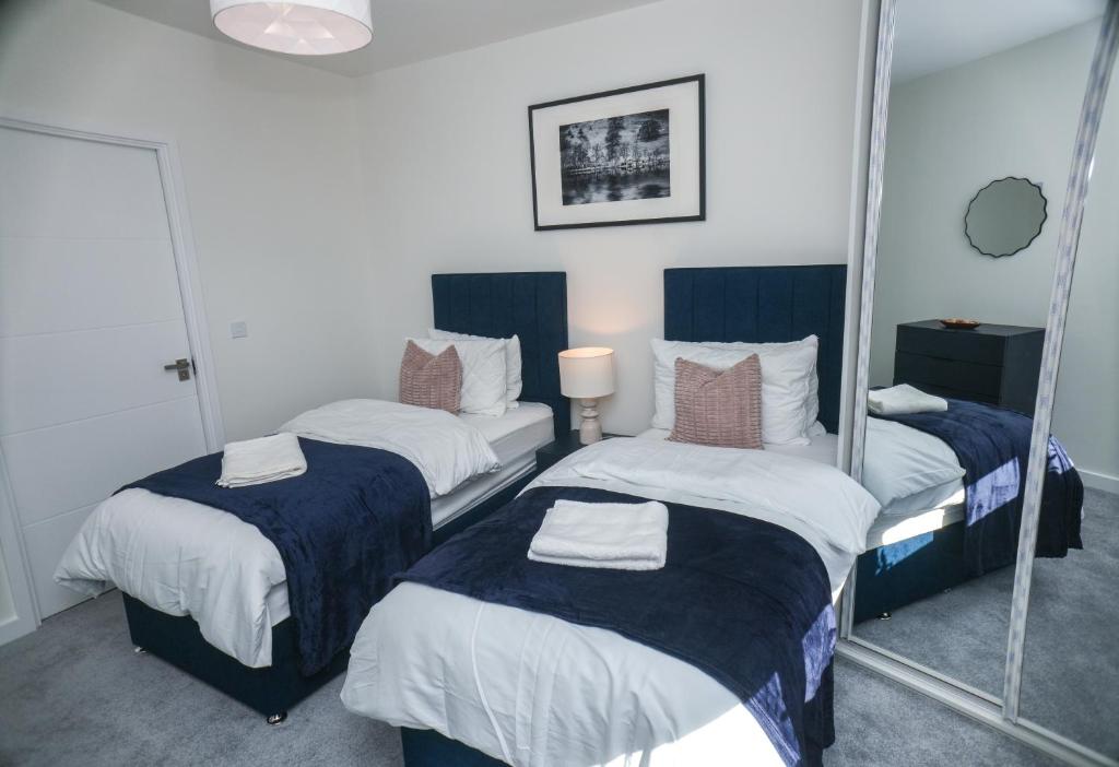 two beds in a room with a mirror at Little Haven Thames view Free Parking Closer to Heathrow in Staines