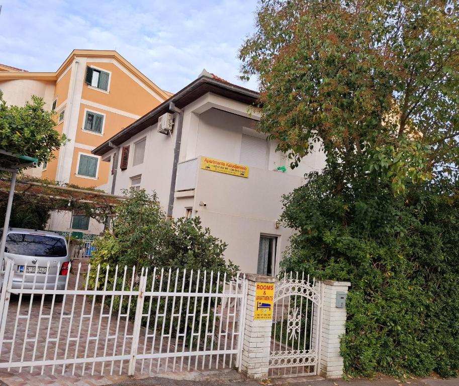 a white fence in front of a white house at Apartments Kaludjerovic in Herceg-Novi