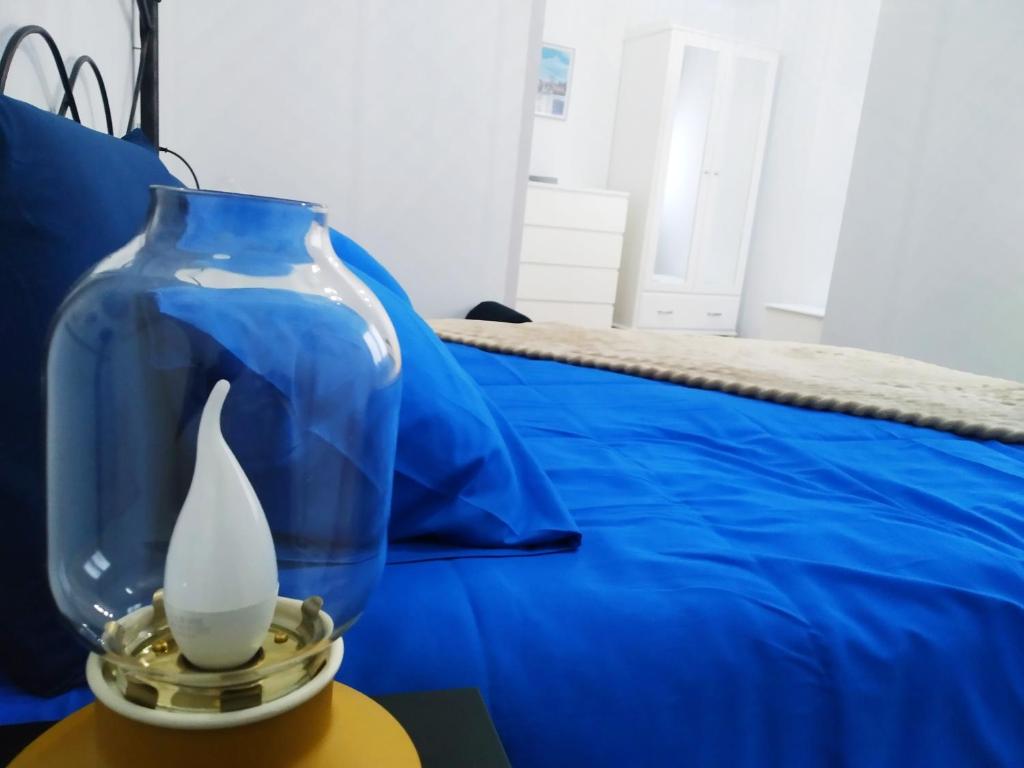 a glass vase sitting on a table next to a bed at LA CASINA DE HUGO AZUL centro Luanco in Luanco