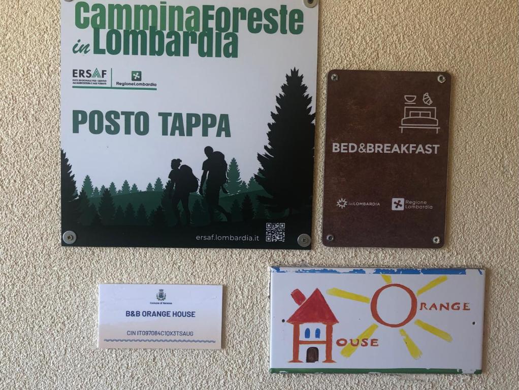 two signs hanging on a wall with a picture of a house at Orange House in Varenna