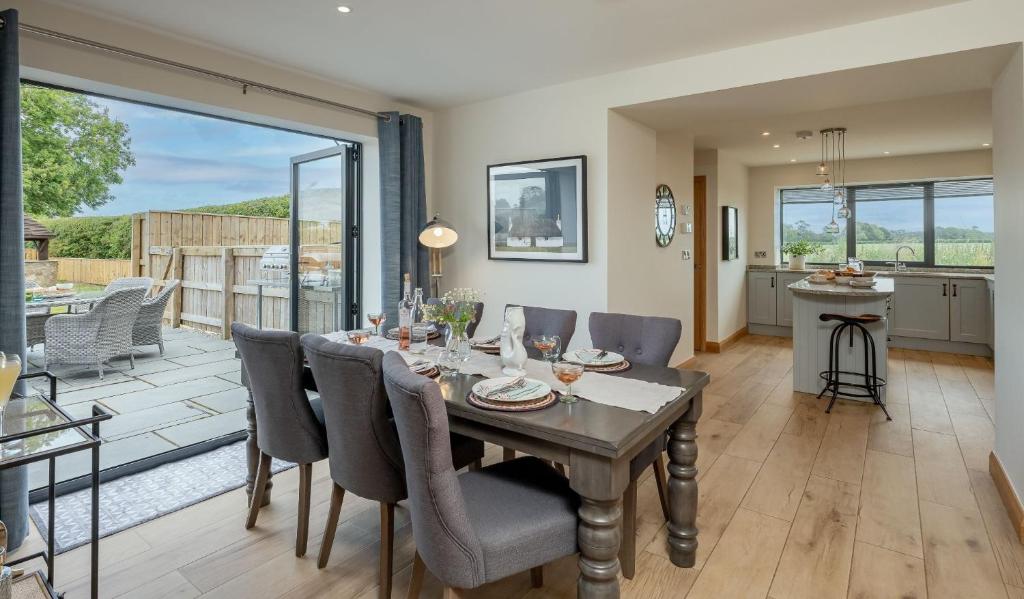 a dining room with a table and chairs and a kitchen at Ellesmere Barn in Bedale