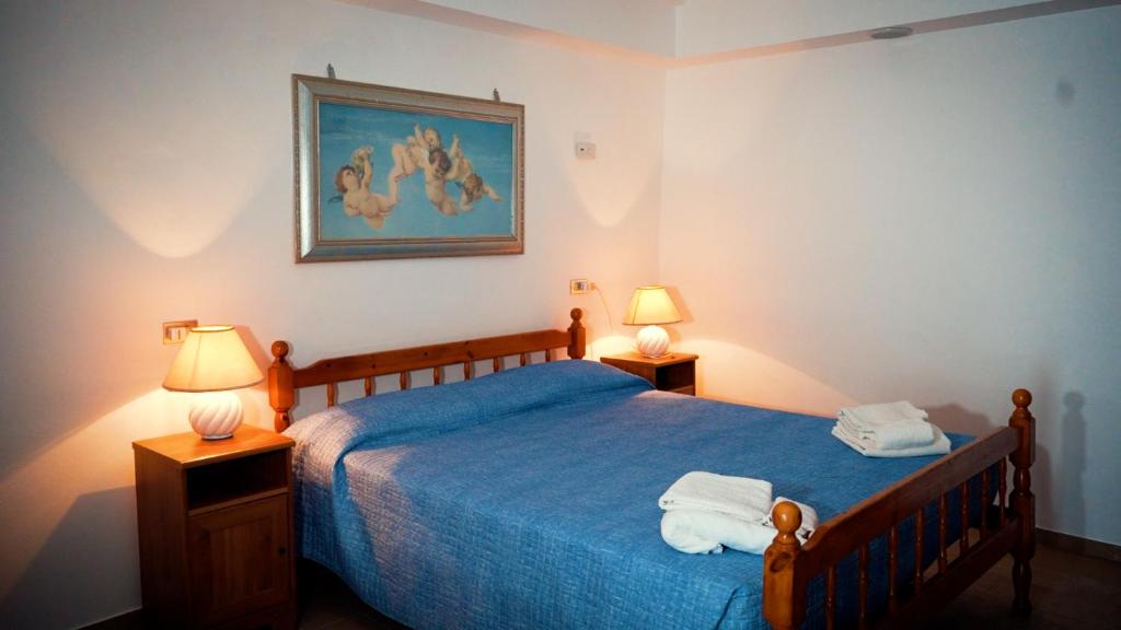 a bedroom with a blue bed with two lamps at Camera Alcova in giardino in Cellino Attanasio