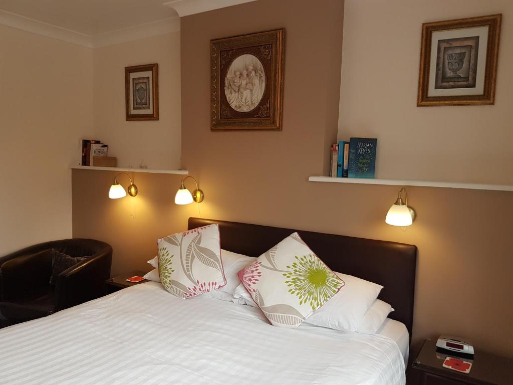 um quarto com uma cama com lençóis brancos e almofadas em Penryn Guest House, ensuite rooms, free parking and free wifi em Stratford-upon-Avon