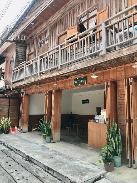 a wooden building with a balcony and a table at นา-ใบบุญ Nabaiboon in Chiang Khan
