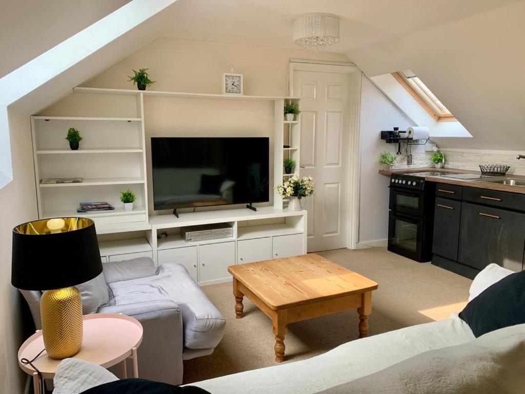 a living room with a tv and a table at The Flat in Tintinhull