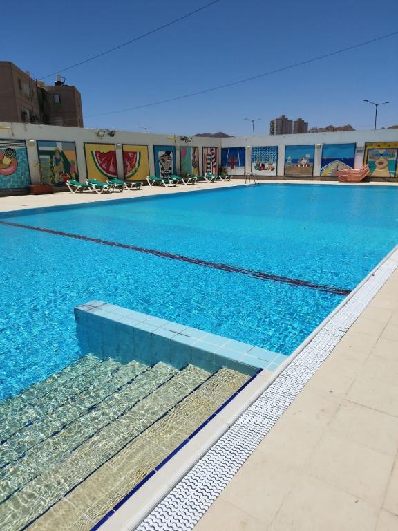 a swimming pool with blue water in a building at Eilat Octopus Apartment - אילת אוקטופוס -שני חדרים וסלון, בריכה בקיץ in Eilat
