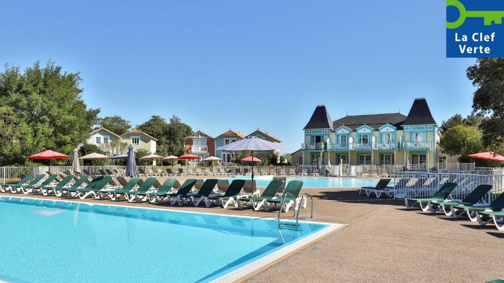 a swimming pool with chairs and umbrellas at Résidence Pierre & Vacances Le Domaine de Bourgenay in Talmont
