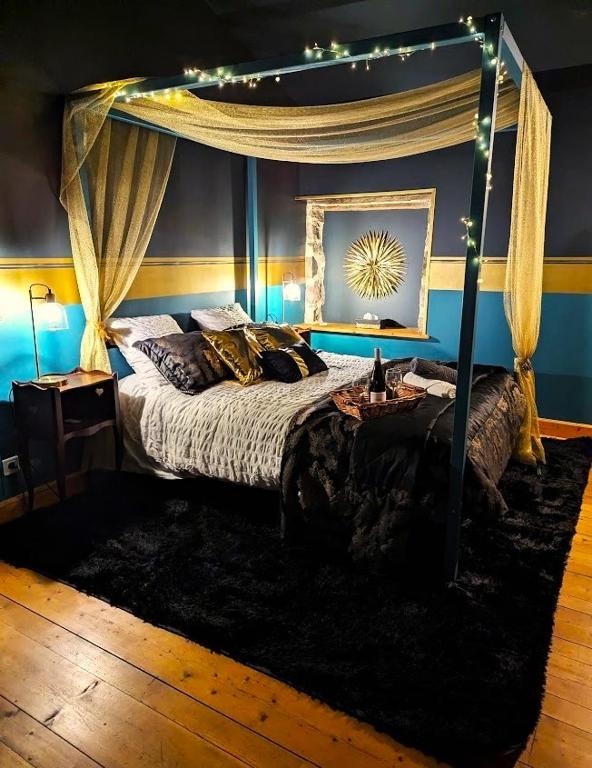 a bedroom with a canopy bed and a table at L'Odyssée de Mélyna entre Beaujolais & Bourgogne in Jullié
