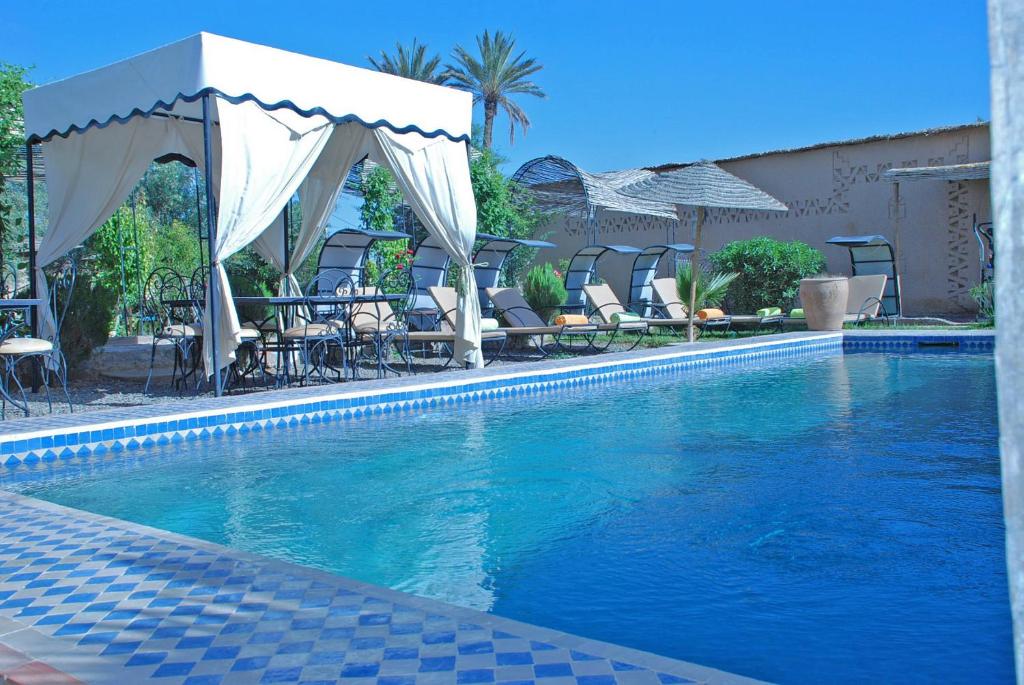 a swimming pool with chairs and umbrellas in front at Chez Laila in Skoura