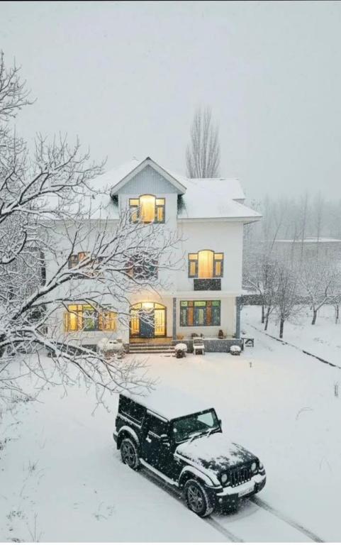 a truck parked in the snow in front of a house at Gulmarg serenity in Khor