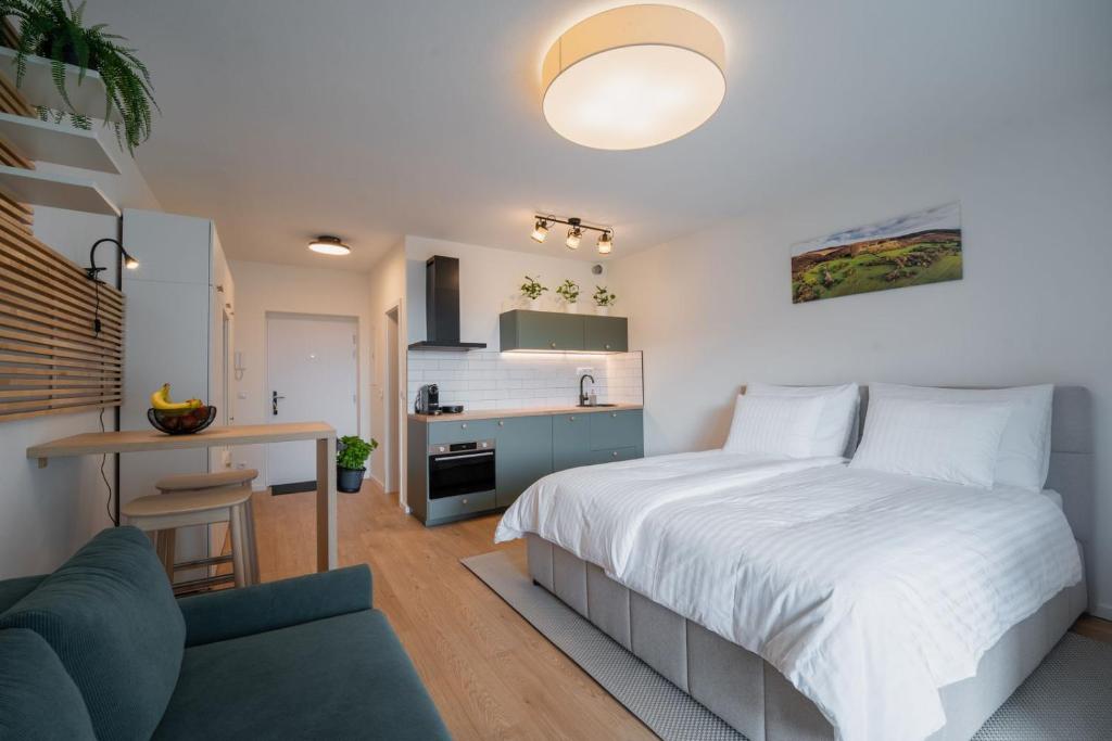 a bedroom with a white bed and a kitchen at Apartmán Sekvoja in Nová Baňa