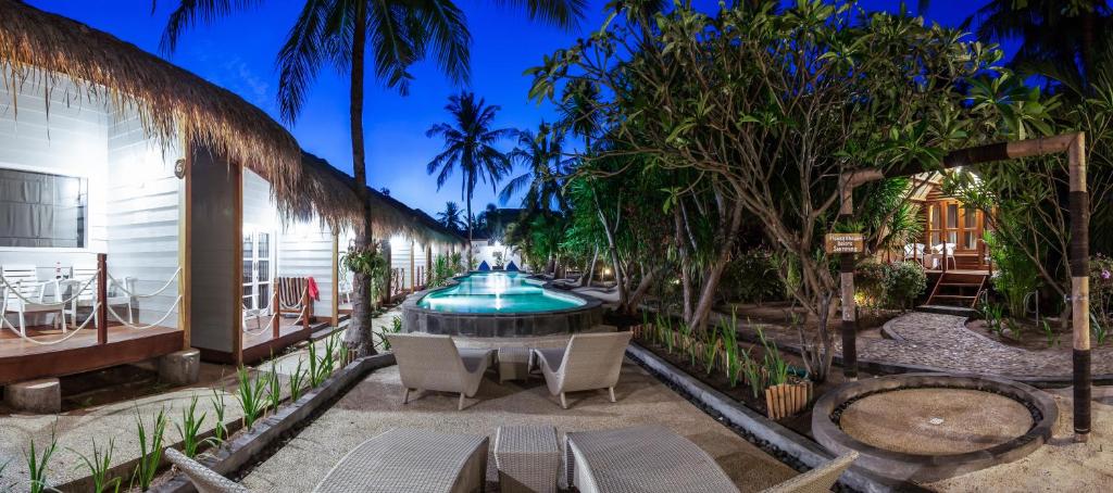 un patio con una fuente, sillas y árboles en Manta Dive Gili Trawangan Resort, en Gili Trawangan