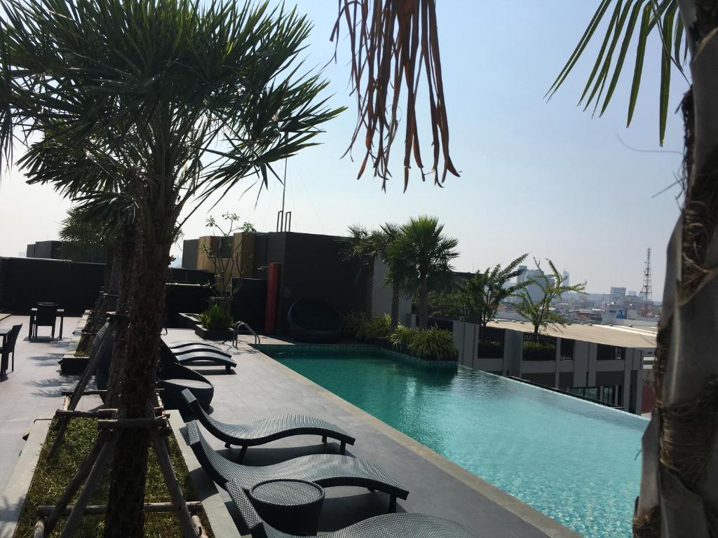 a swimming pool on top of a building with palm trees at The Chezz by Apple & Frank in Pattaya Central