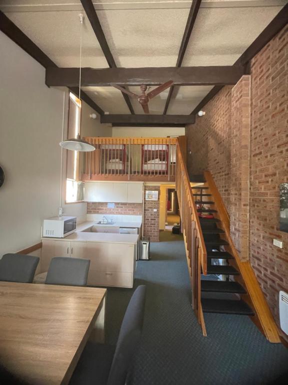 a kitchen and dining room with a brick wall at Alpine Gables Apartment in Jindabyne