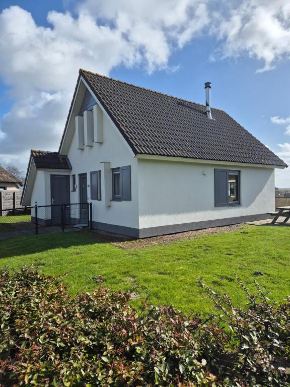 a white house with a black roof at vacation home 68 in Tzummarum