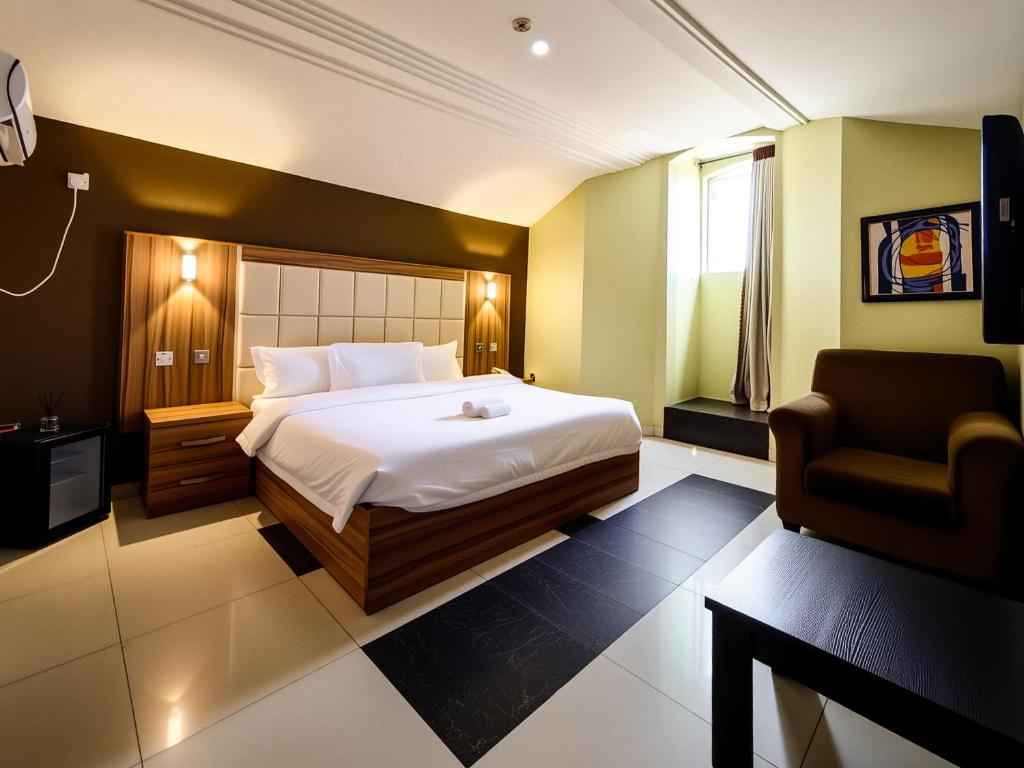 a bedroom with a bed and a chair in it at Aotel Hotel Lagos Ago in Lagos