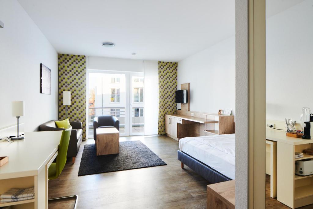 a bedroom with a bed and a living room at ADAPT APARTMENT HOTEL Giessen in Gießen
