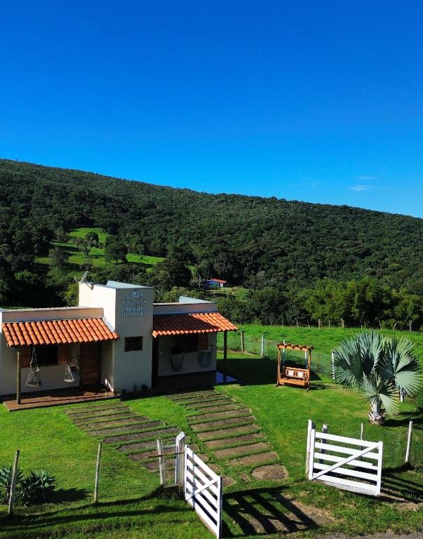 a house with a white fence in front of a hill at Pousada Império de Minas in Capitólio