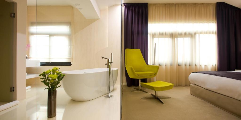 baño con bañera, cama y silla amarilla en Hotel Vila Class, en Satu Mare