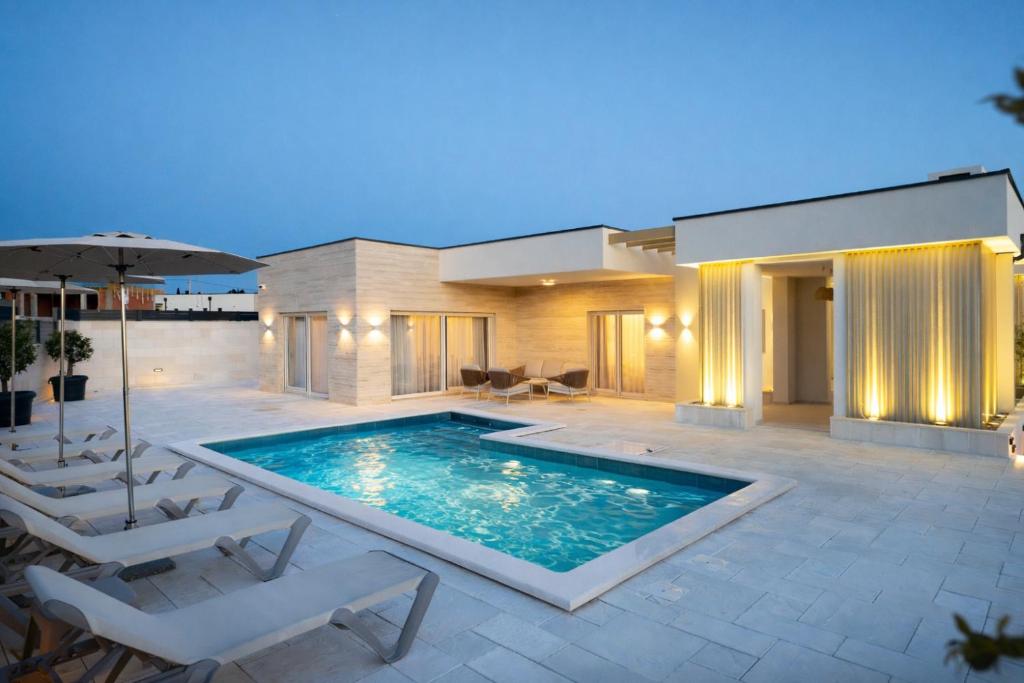 a house with a swimming pool and two chairs and an umbrella at Villa Stone in Smoković
