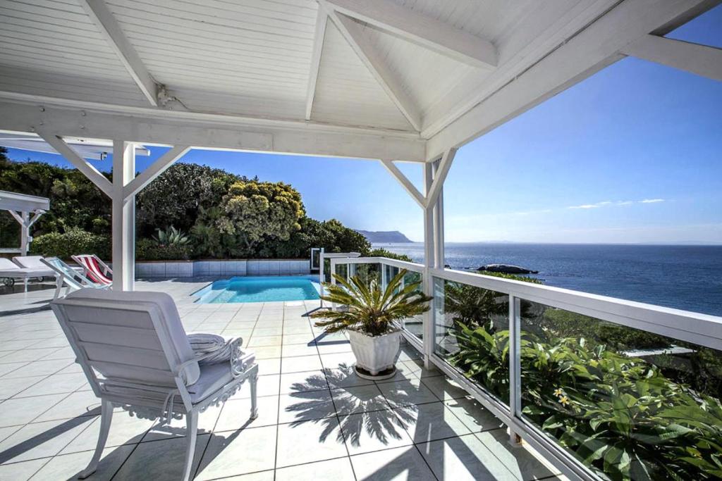 a porch with a white chair and a view of the ocean at The Seaside View in Simonʼs Town