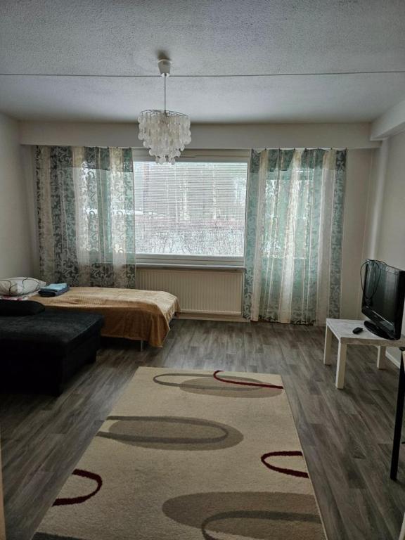 a living room with a bed and a large window at Rivitaloyksiö Vilppulassa in Vilppula