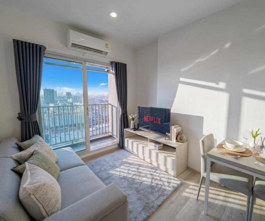 a living room with a couch and a large window at Amazing High Floor Luxury Studio in Sathani Ban Hua Mak