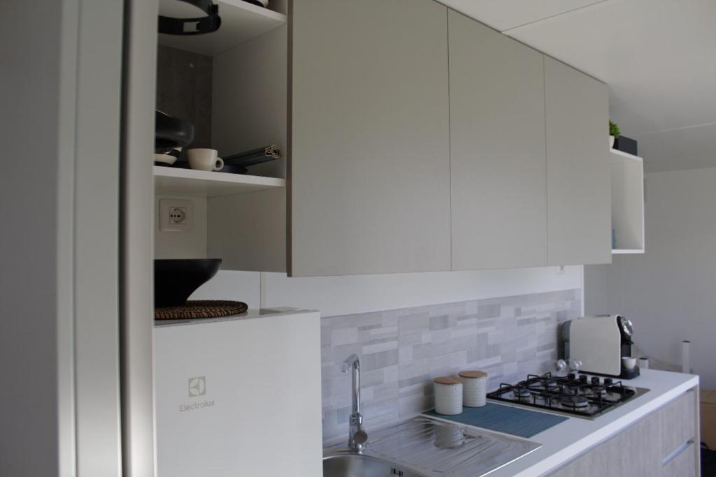 a white kitchen with a sink and a stove at Villaggio Camping Adria in Casal Borsetti