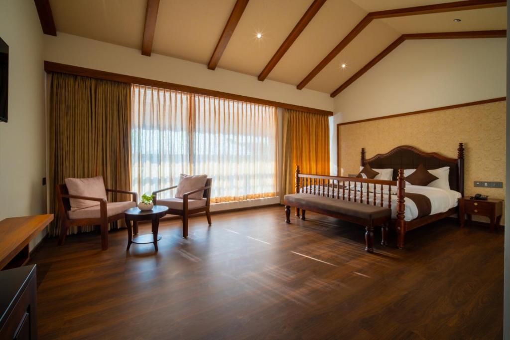 a hotel room with a bed and a couch and chairs at VIHARA By CMK in Cochin