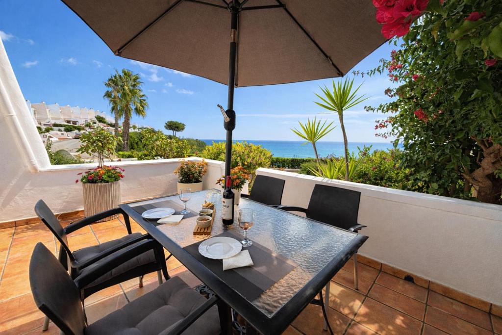 a table with chairs and an umbrella on a patio at Luxury House - Montesol ALBERT VILLAS in Alcossebre
