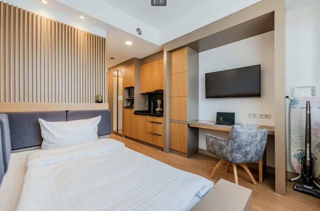 a hotel room with a bed and a desk and a television at SOLWO Suites Berlin Charlottenburg in Berlin