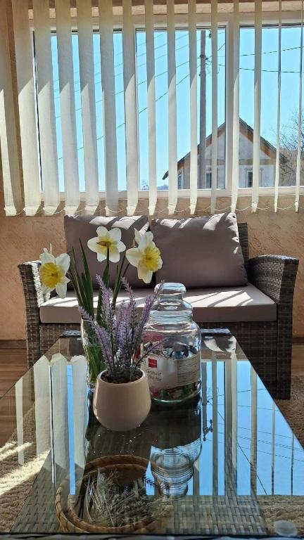a glass table with flowers on top of a balcony at Seosko domaćinstvo Rada in Papratište