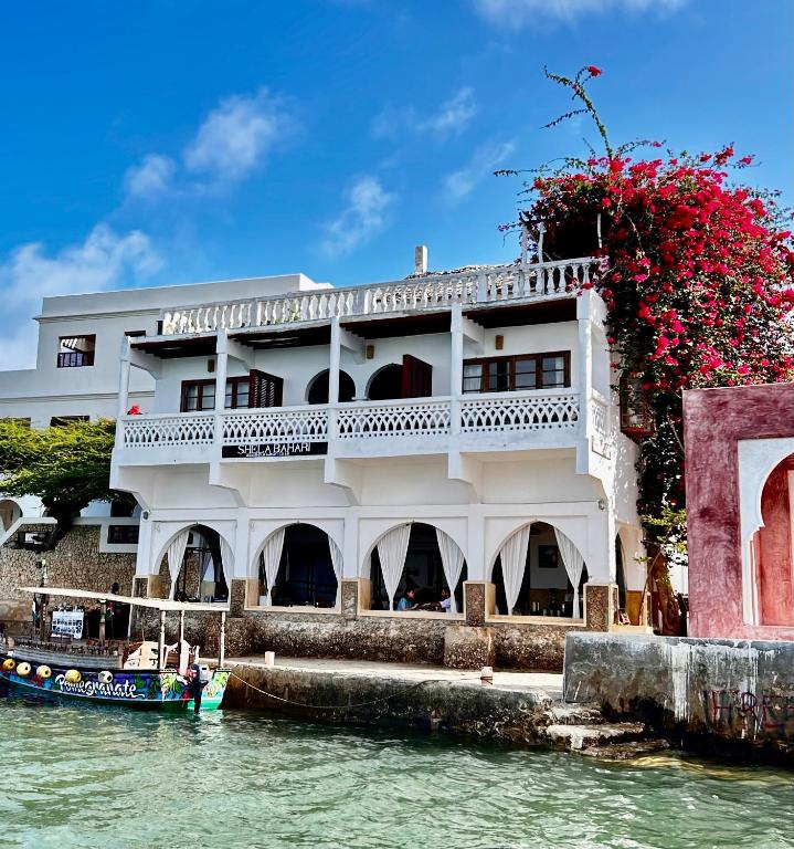 a building on the water with a boat in front at Shela Bahari in Shela