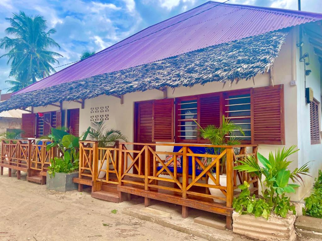 a house with red shutters and a porch at Aluna Beach House Nungwi in Nungwi