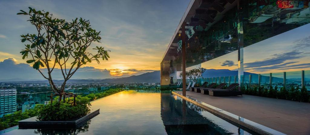 a building with a pool in front of a city at Deluxe 2-Bedroom Suite with Pool & Gym in Chiang Mai