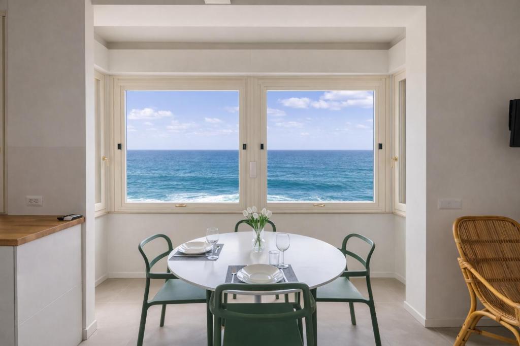 a dining room with a table and chairs and a large window at Effe's apartment- ARYA seaview -parcheggio gratuito in Alassio