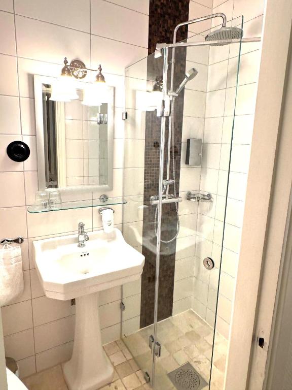 Mała jasna łazienka z umywalką na cokole i przeszklonym prysznicem, schludna i nowoczesna.