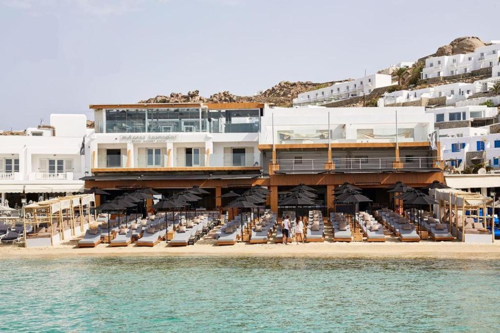 ein Gebäude am Strand mit Stühlen und dem Wasser in der Unterkunft Mykonos Kosmoplaz Beach Resort Hotel in Platis Gialos