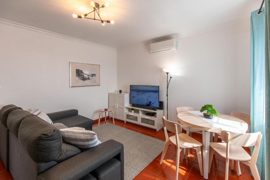 a living room with a couch and a table and a television at Casa do Lado, Flores Açores in Lajes das Flores