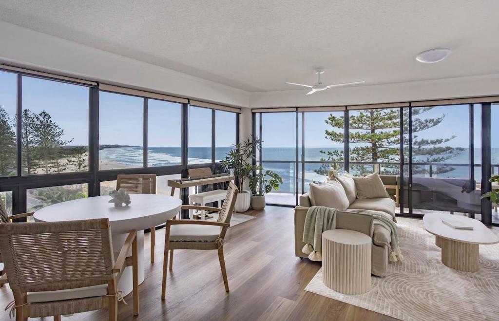 a living room with a couch and a table and chairs at Summer Cove on the Ocean with Pool in Coolum Beach