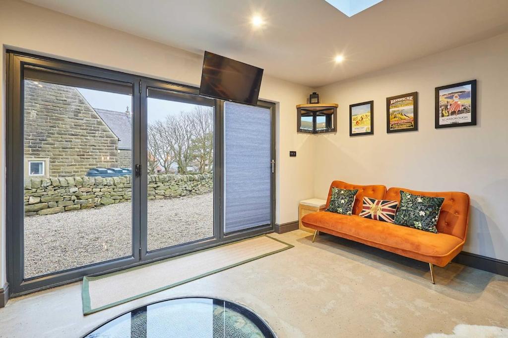 a living room with an orange couch and a large window at The Churchside Well in Ravenscar