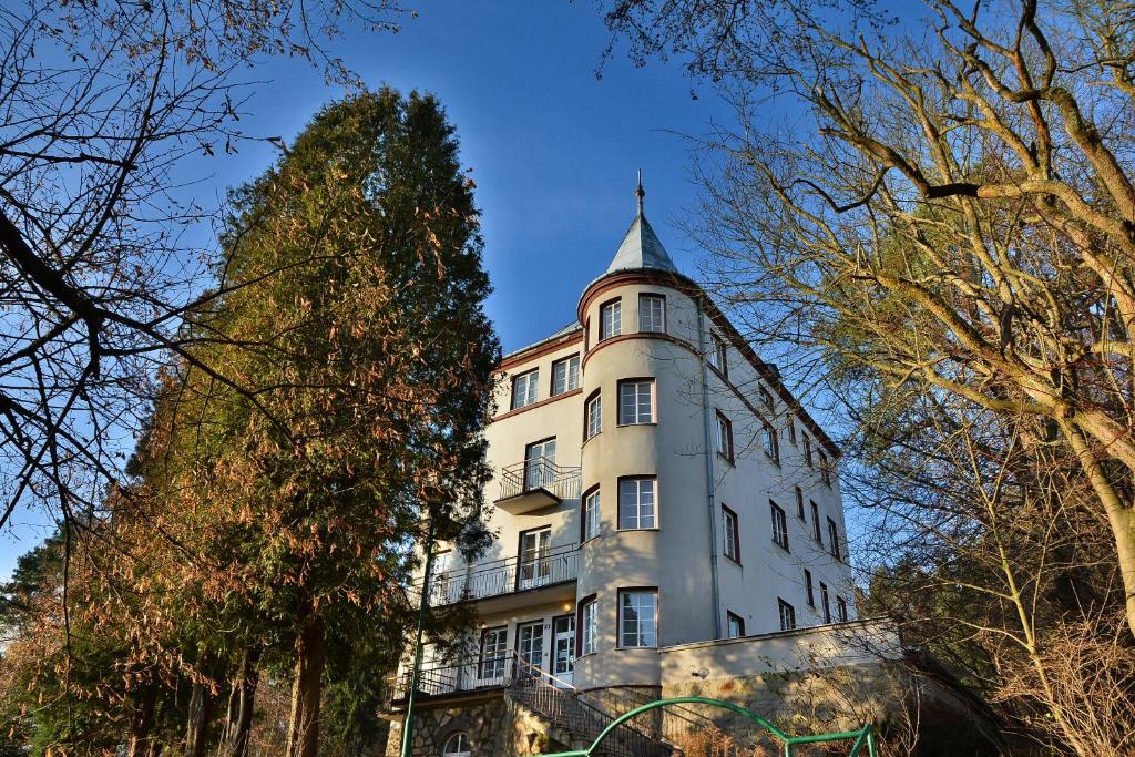 um edifício branco alto com uma torre em cima em Rezydencja Zamek em Krynica-Zdrój